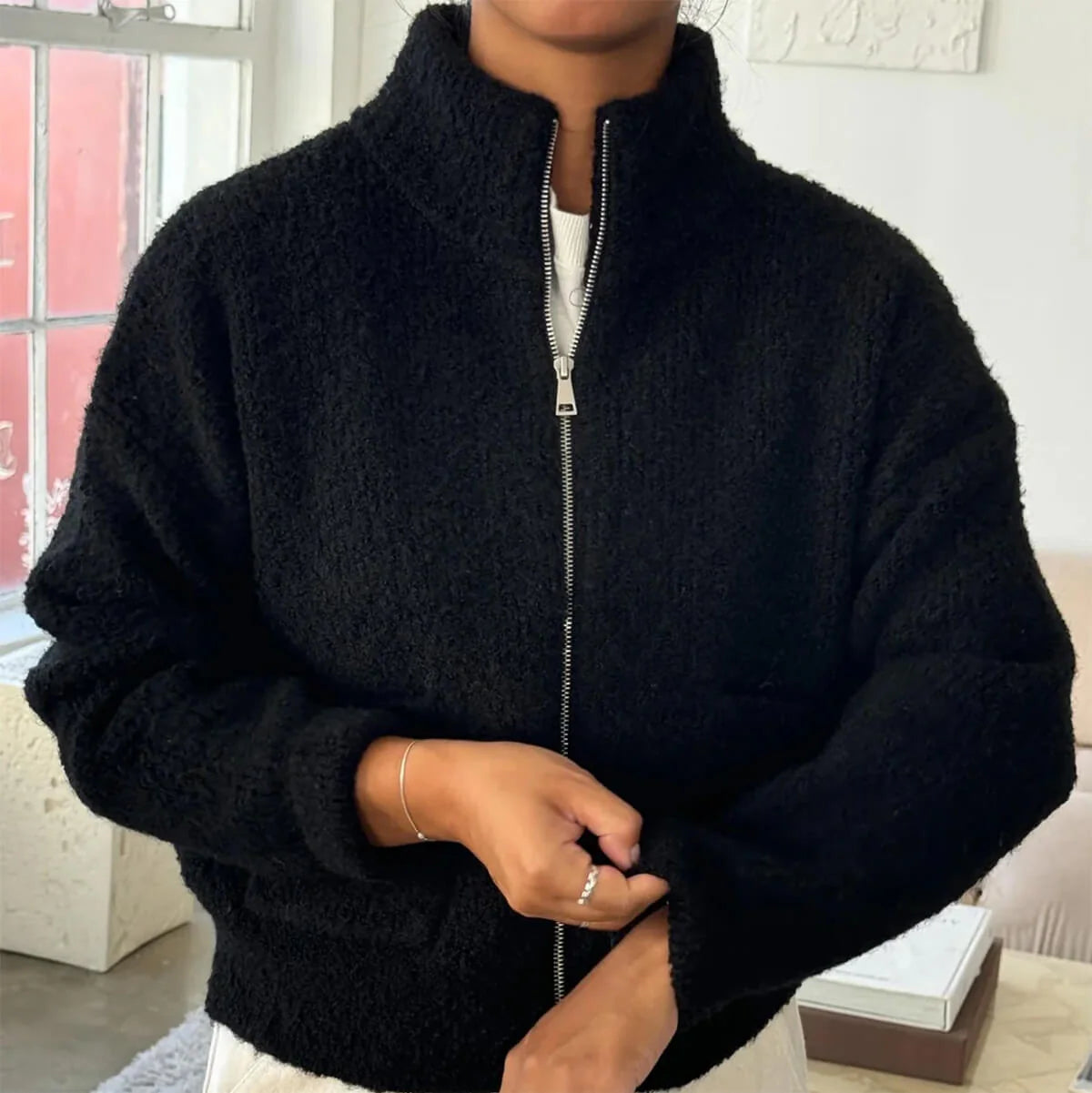 Person wearing a black zip-up sweater indoors