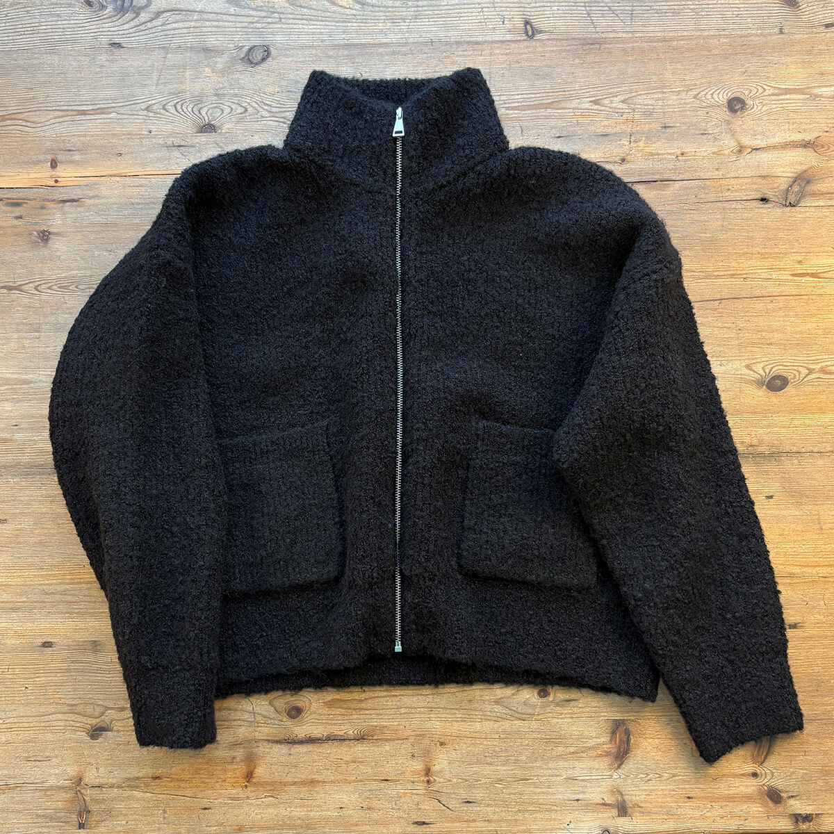 Black jacket with a zipper on a wooden surface