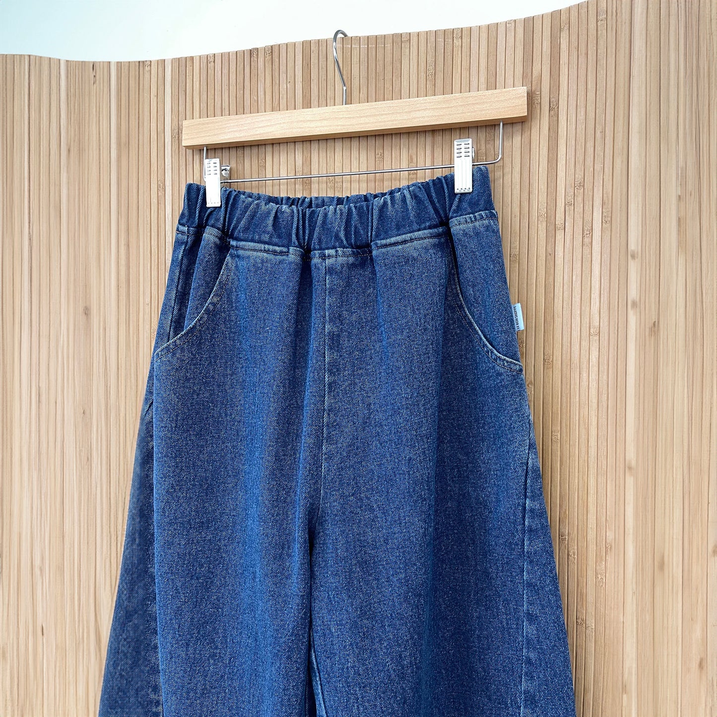 A close up the  high-waisted Arc Pants made from heavyweight denim, featuring a cropped length and slightly curved leg shape. The design includes unique side panels and deep pockets, perfect for casual wear.