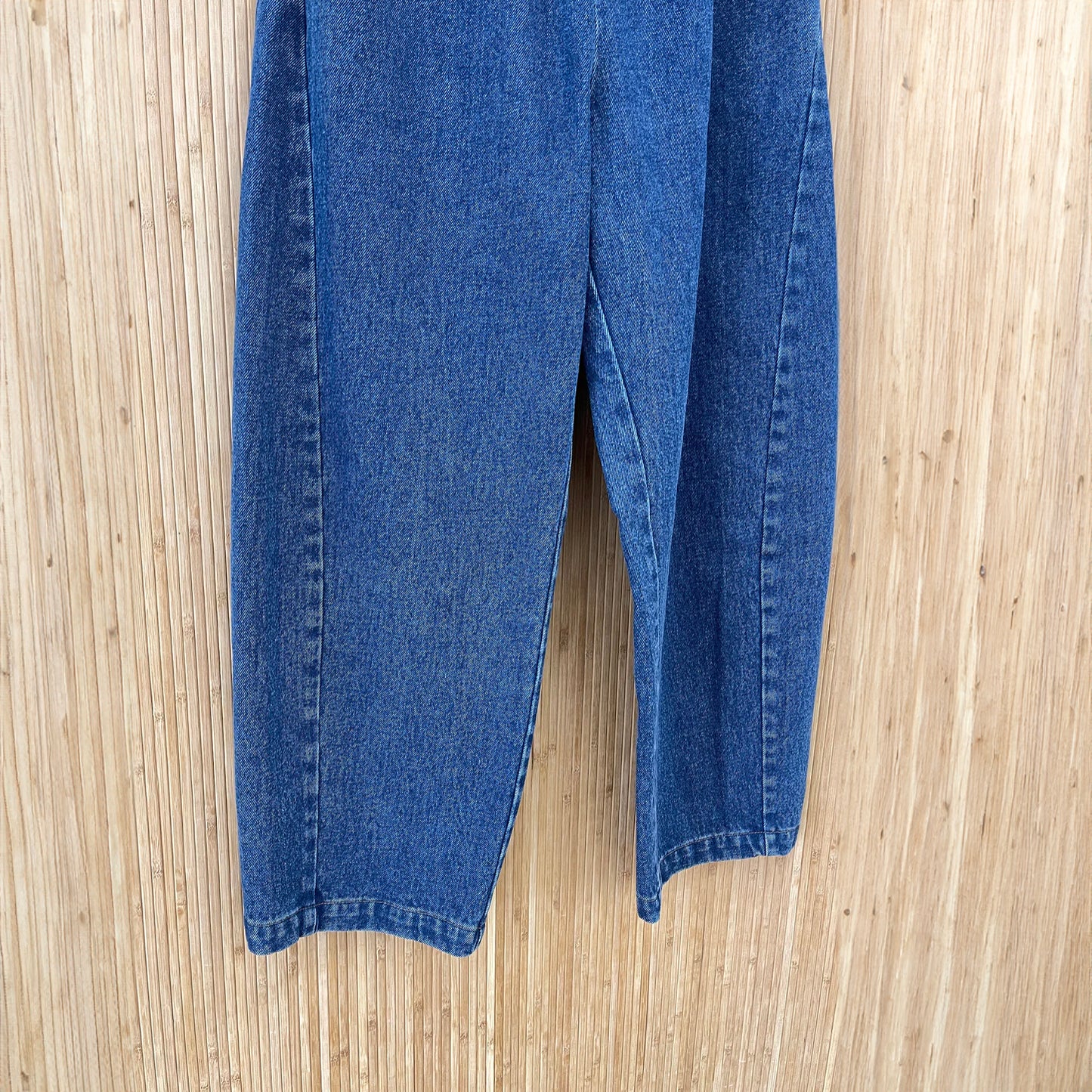 A close up of the legs of the stylish high-waisted Arc Pants made from heavyweight denim, featuring a cropped length and slightly curved leg shape. The design includes unique side panels and deep pockets, perfect for casual wear. Displayed with a neutral background to highlight the pant's versatile style.