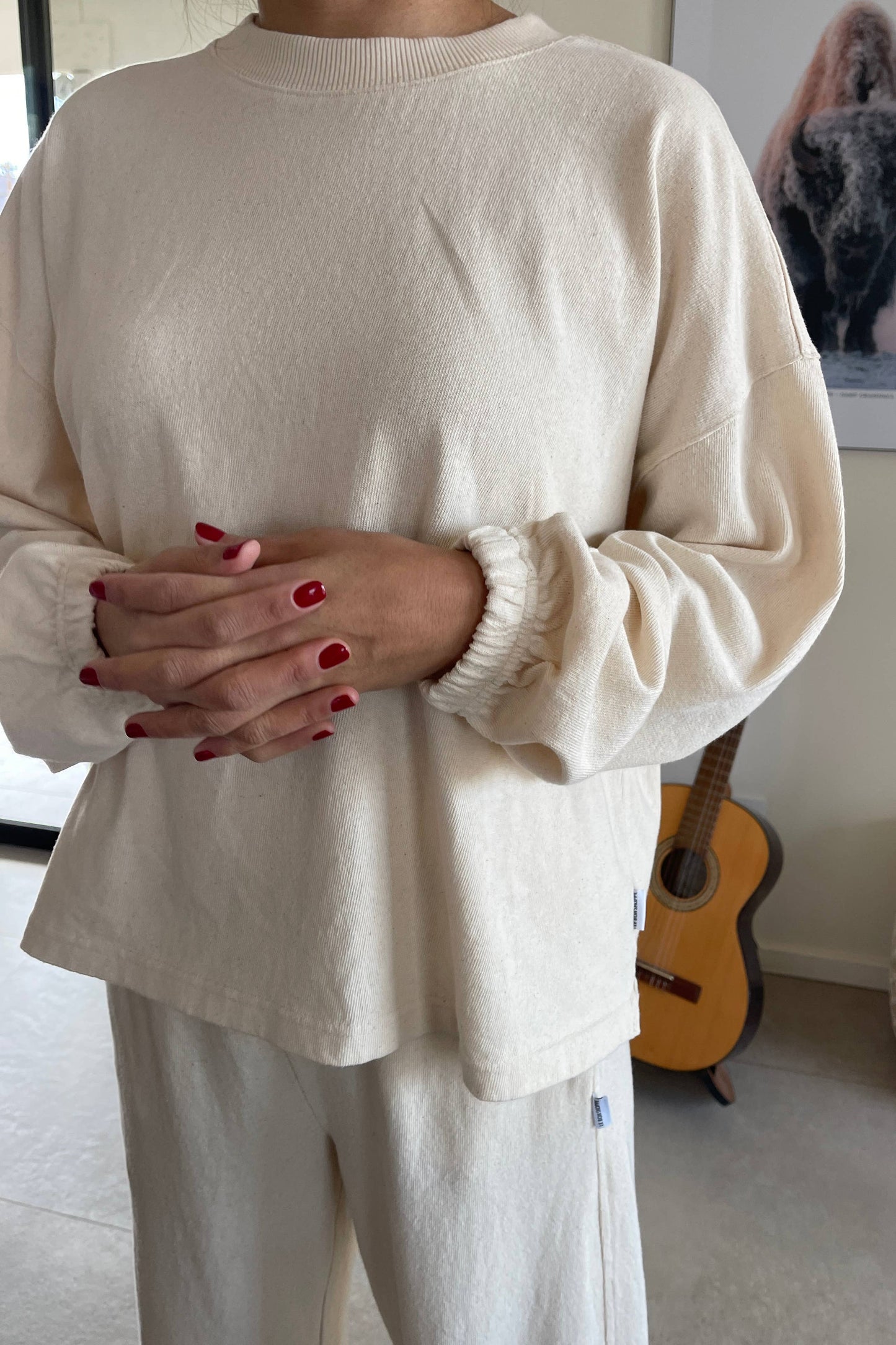 A close-up shot of the dropped shoulders and ruched sleeves, styled with matching natural cotton trousers.