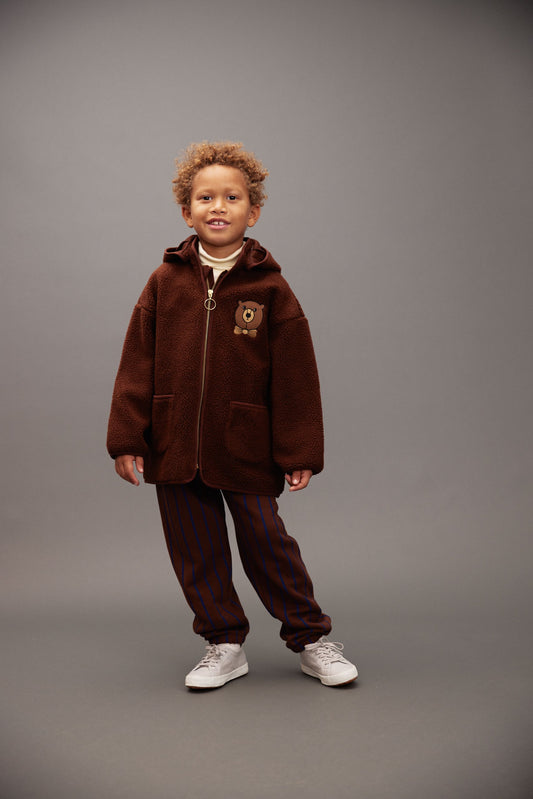 Child wearing a brown outfit with a hood on a gray background