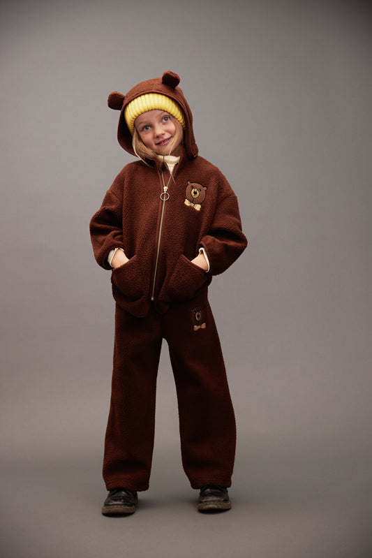 Child wearing a brown bear-themed outfit on a gray background