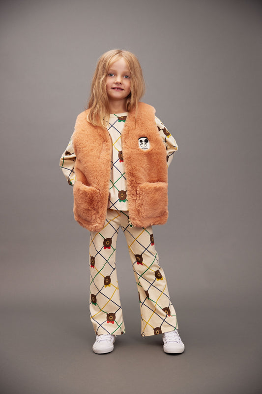 Child wearing a brown fur vest, patterned sweater, and pants on a gray background