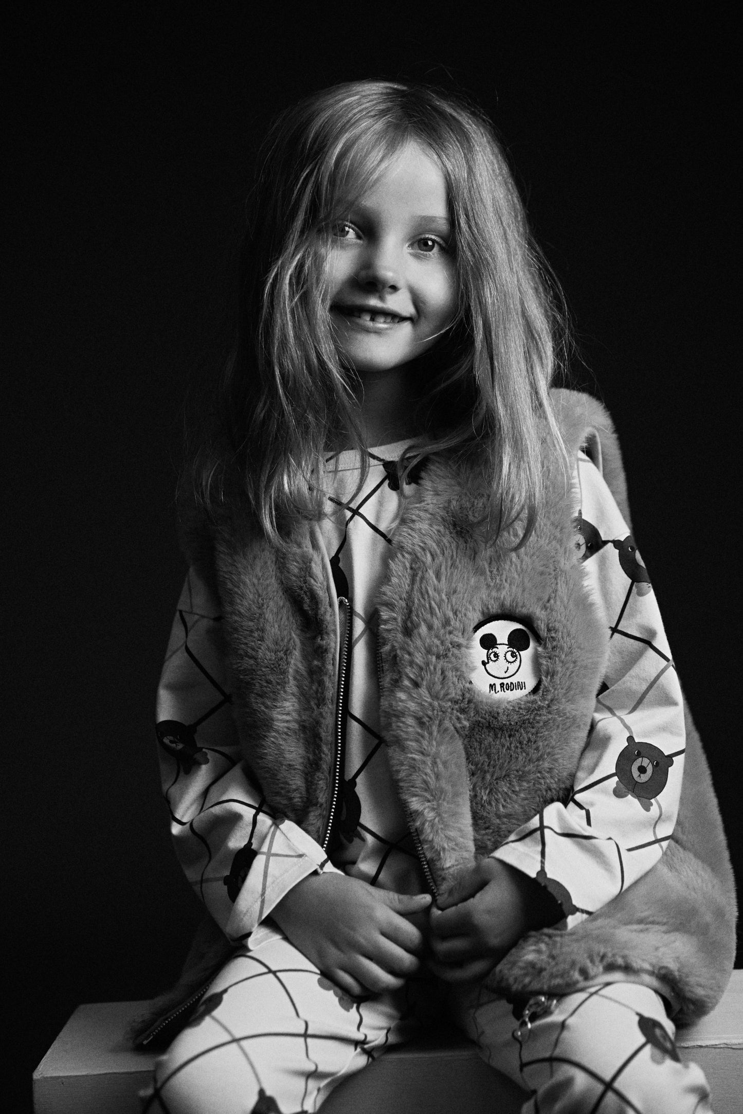 Black and white photo of a child wearing a patterned outfit with a hood.
