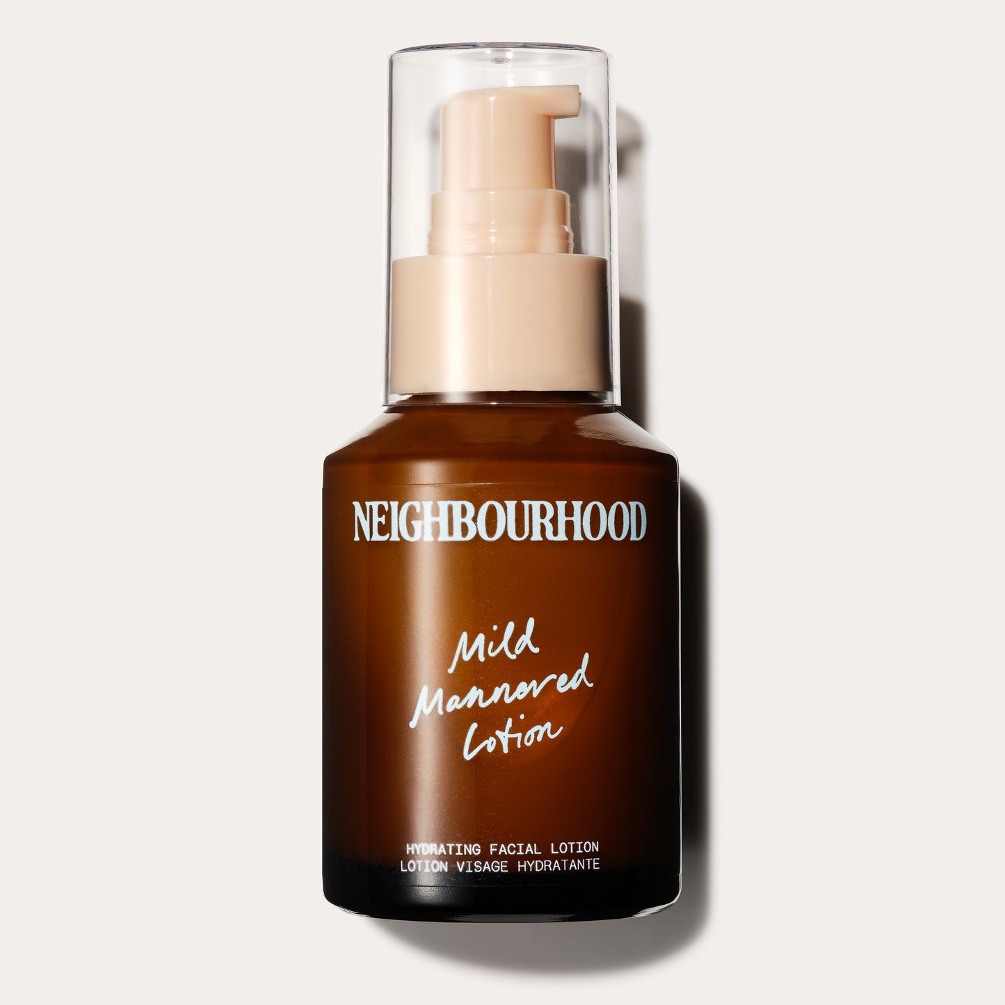 A brown glass bottle with a cream pump dispenser and clear cap, labeled "Neighbourhood Mild Mannered Lotion." The packaging features soft blue handwritten-style text and indicates it is a hydrating facial lotion.