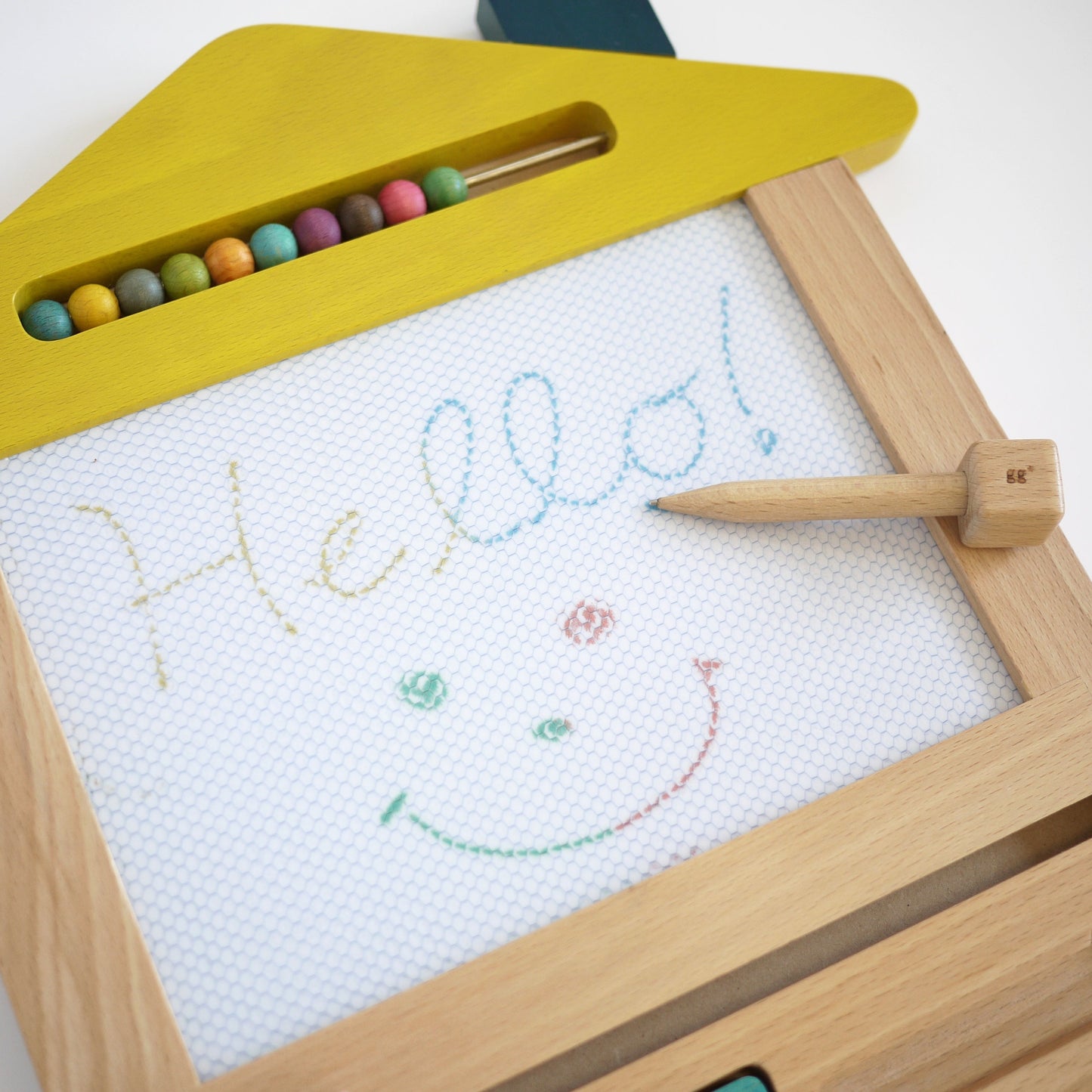 Wooden drawing board with colourful chalks and a child's drawing on a white background