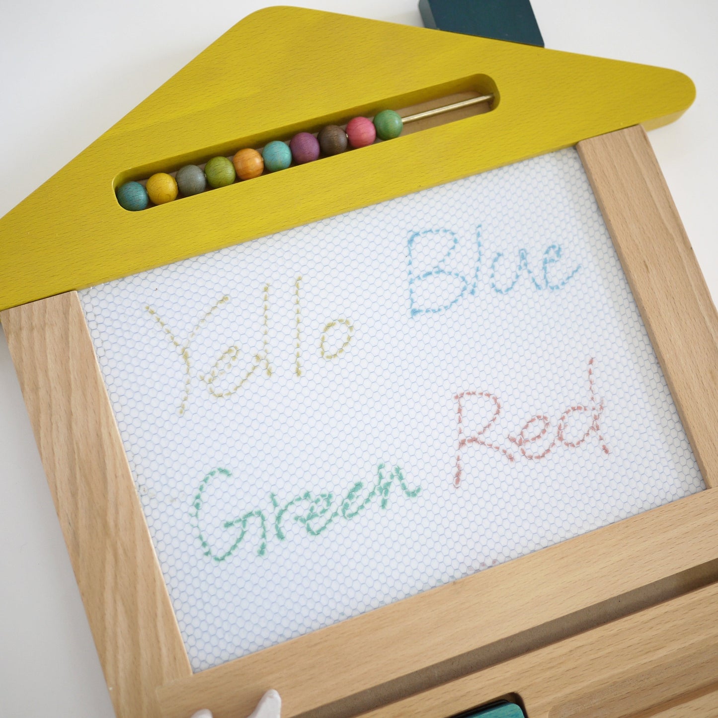 Wooden toy with colourful beads and a whiteboard with color names written on it.