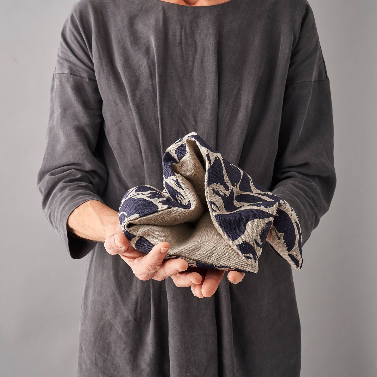 Person holding a folded wheat bag with a pattern against a gray background