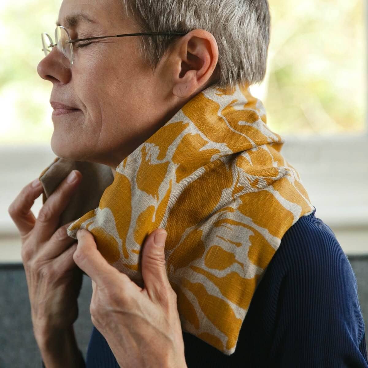 Person wearing a yellow patterned wheat bag with a blurred background