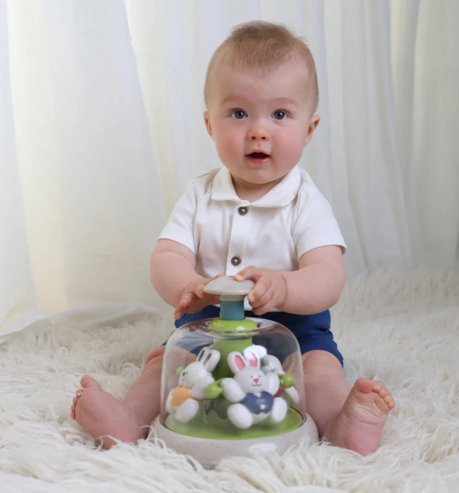 Baby playing with a toy featuring rabbit characters on a white background