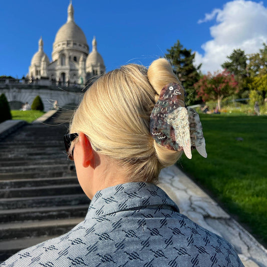 A woman wearing the pigeon hair claw clip in an elegant updo, with the Sacré-Cœur Basilica in the background.
