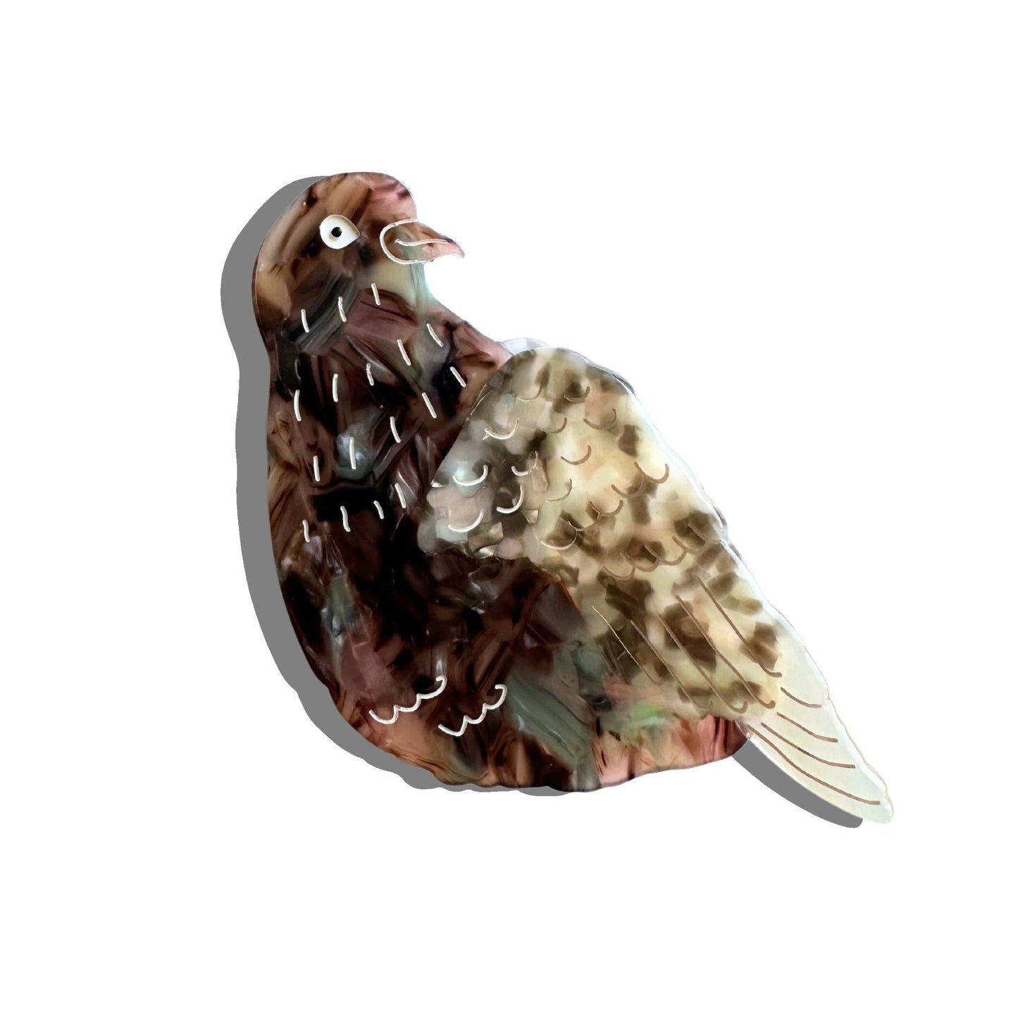 Close-up of a pigeon-shaped hair claw clip made from cellulose acetate, featuring a hand-painted brown and grey feather pattern with white details.