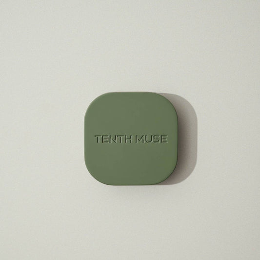 An overhead shot of the green/matcha square refillable compact, against a white background, for the tenth muse solid perfume balms that has 'TENTH MUSE' lightly carved into the compact.