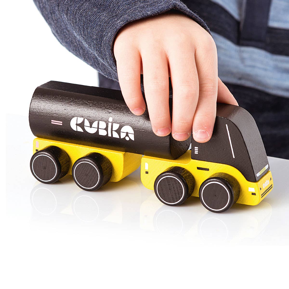 Toy truck with a hand lifting one of its black cylindrical sections, on a white background.