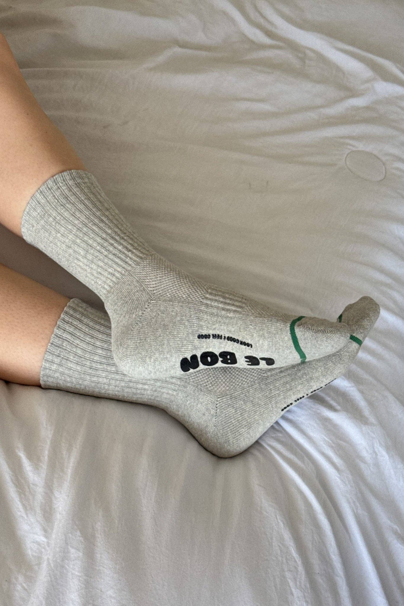 Gray socks with text on a white bed sheet