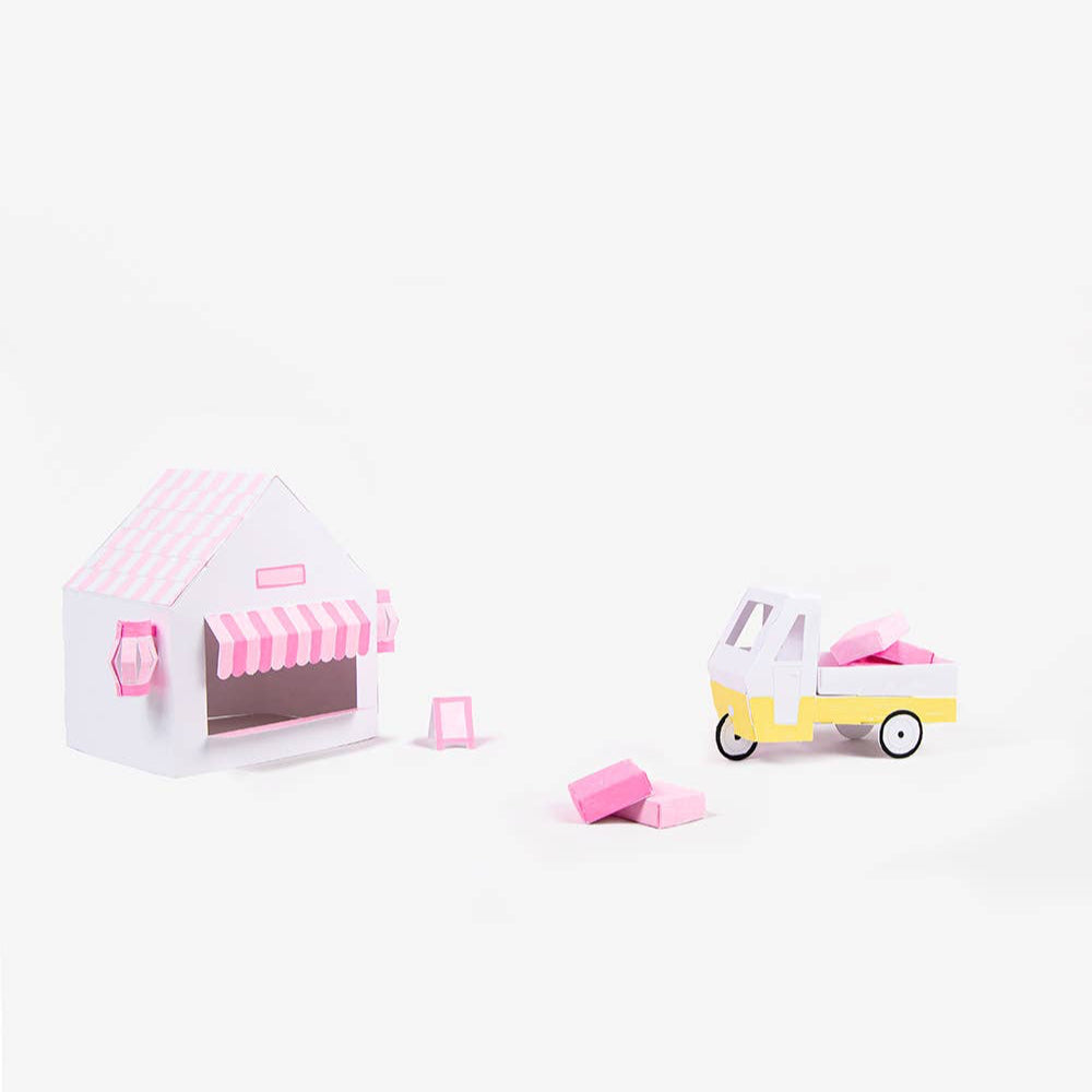 Small toy house with pink roof and canopy, and a toy car on a white background