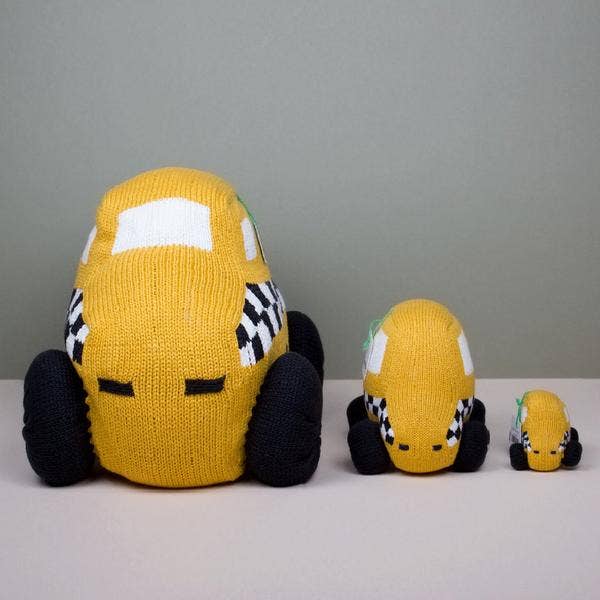 Three knitted taxi toys of different sizes on a neutral background