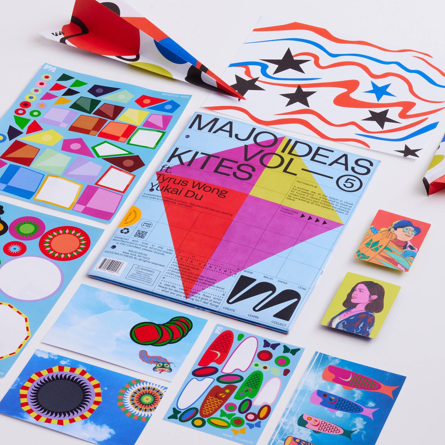 Colorful art supplies including kites and design sheets on a white background
