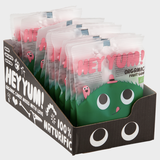 Display box of HEY YUM! organic fruit gummy candy pouches with playful green character design and pink logo branding