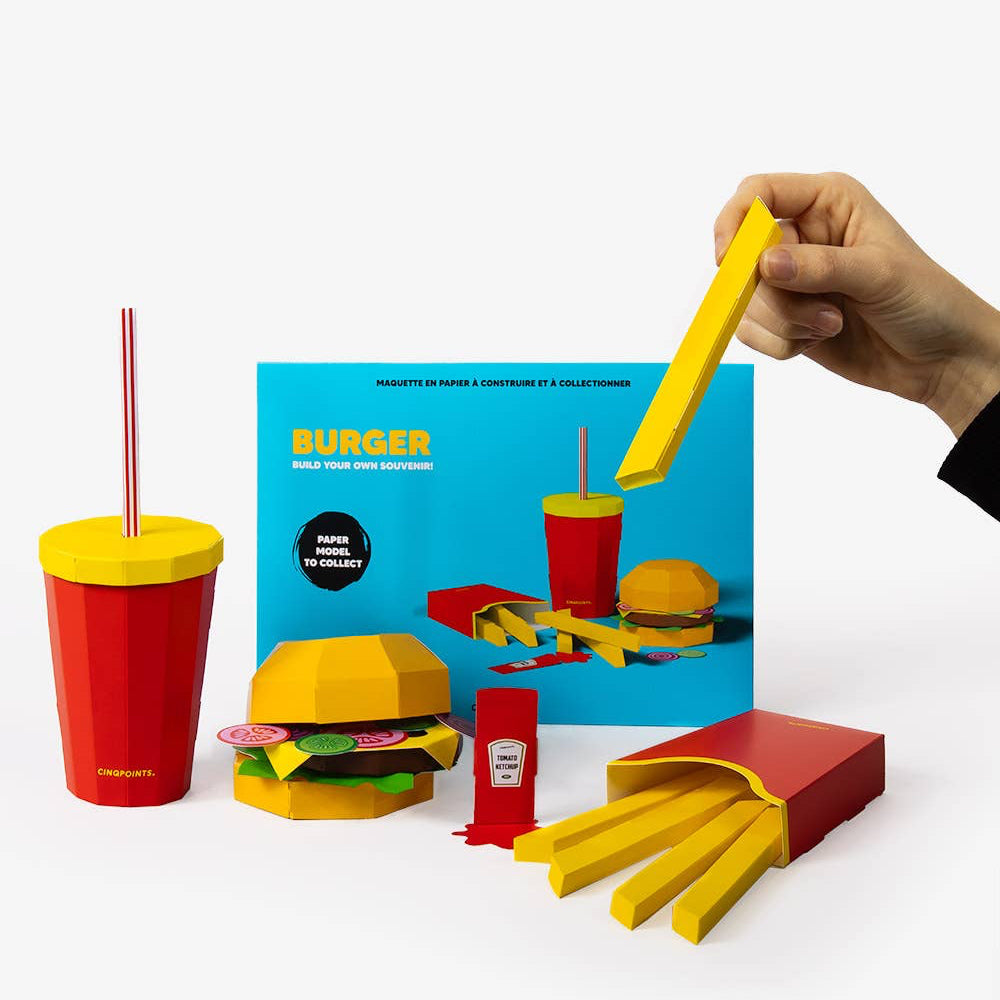 Colorful toy set including a burger, fries, and drinks with a hand holding a yellow straw.