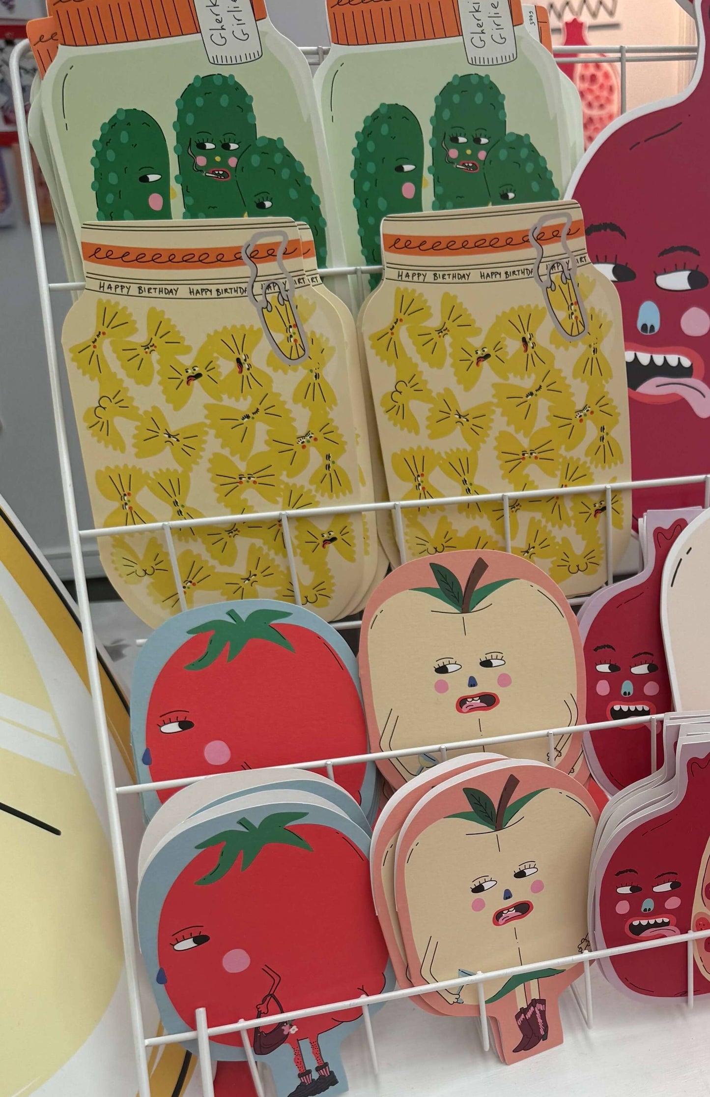 Display of colorful face cards with cartoon designs on a white rack.