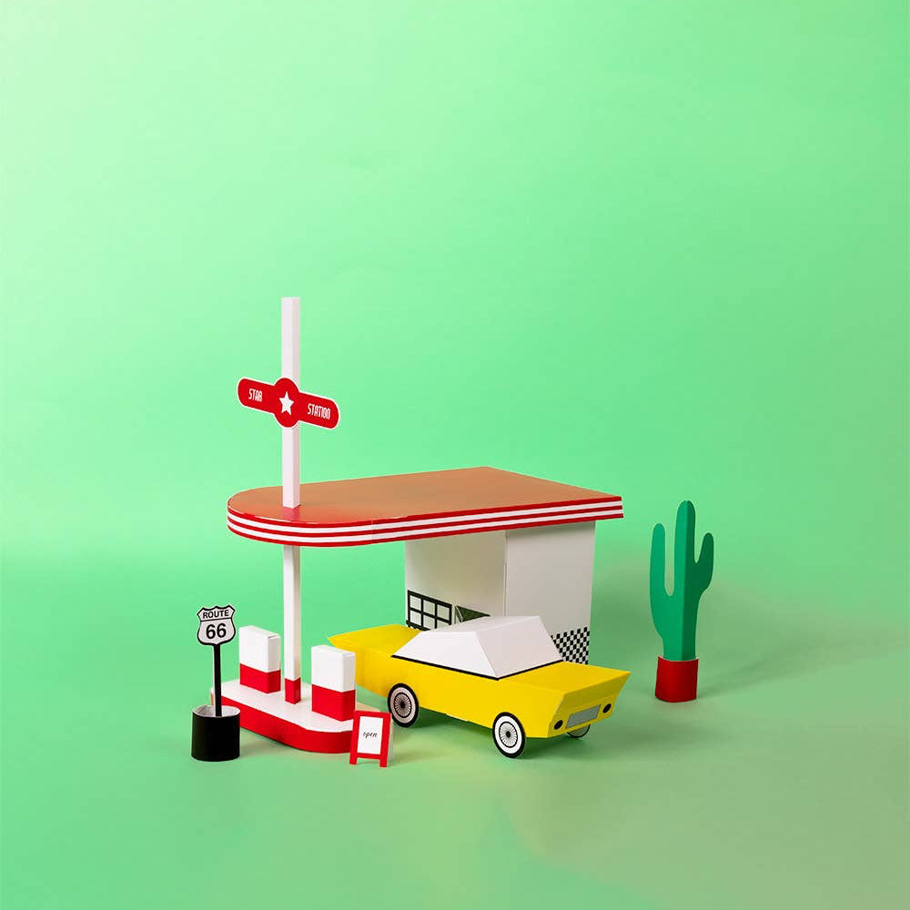 Toy gas station with a yellow car on a green background