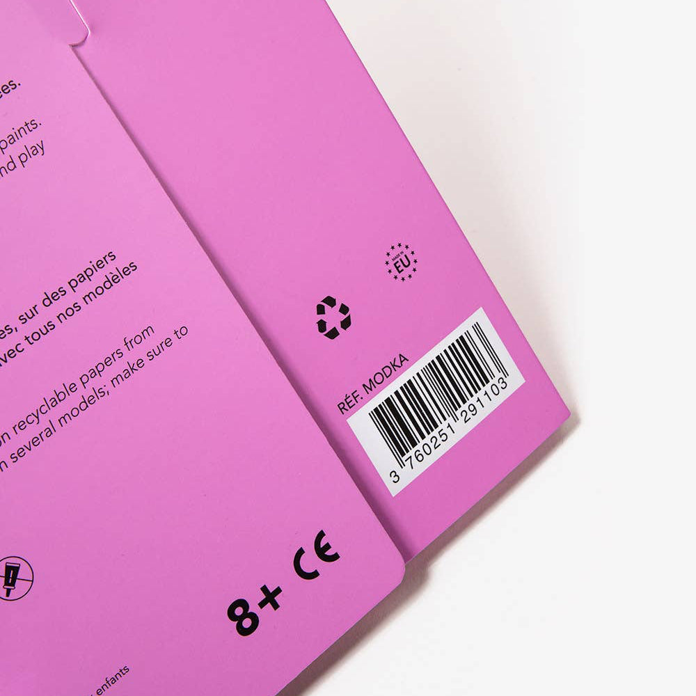 Close-up of a pink product packaging with text and a barcode on a white background