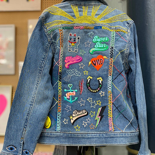 Denim jacket with colorful patches and embroidery on a blurred background
