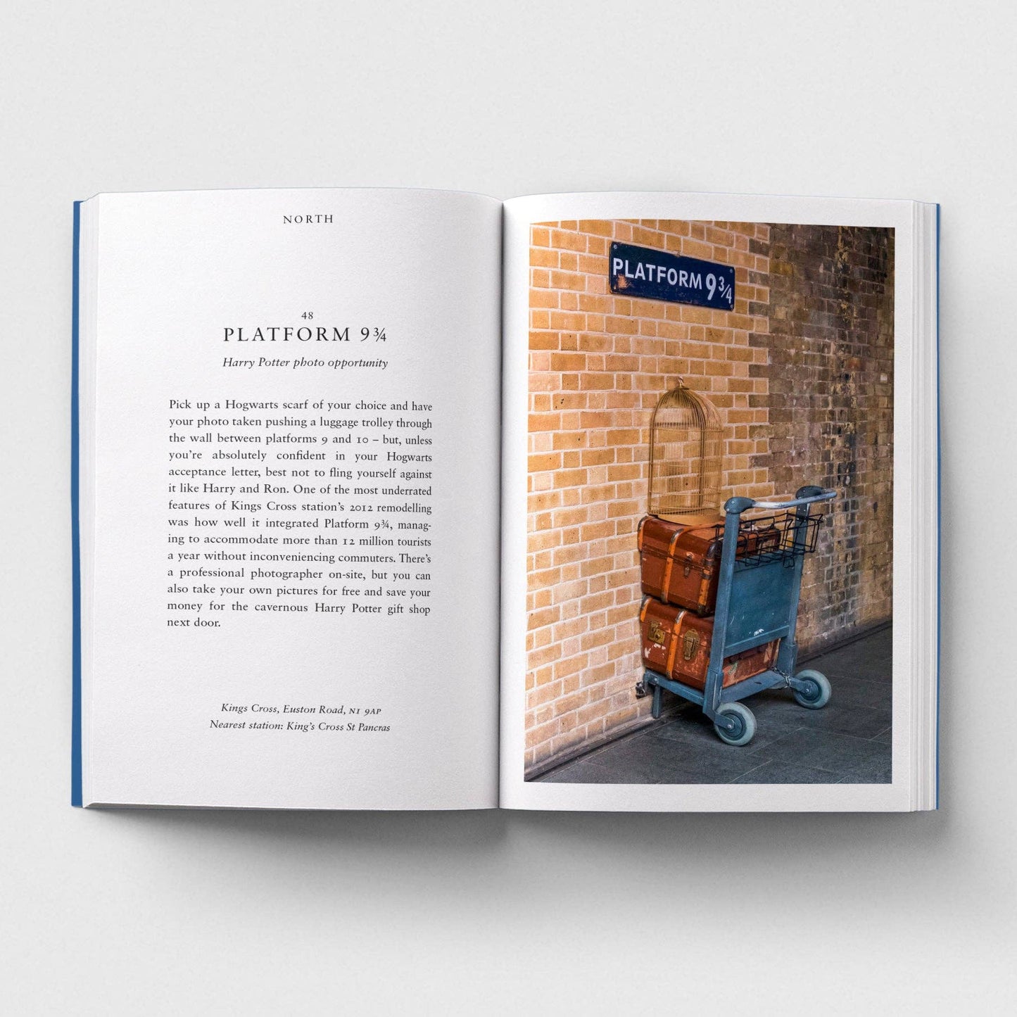 Open book showing text on one page and a photo of a luggage trolley against a brick wall on the other.