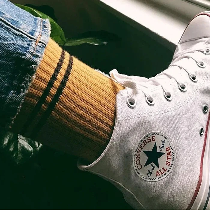 White Converse sneaker with a green star logo on a blurred background
