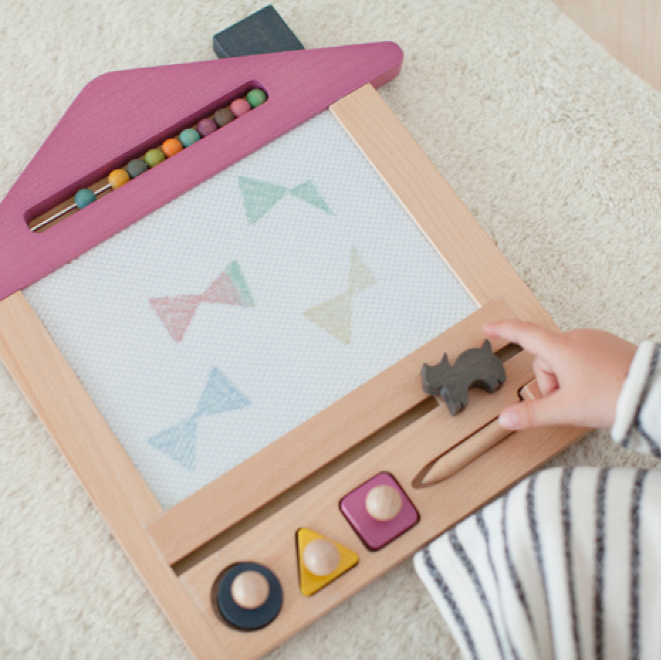 Child playing with a magnetic drawing board on a carpeted floor
