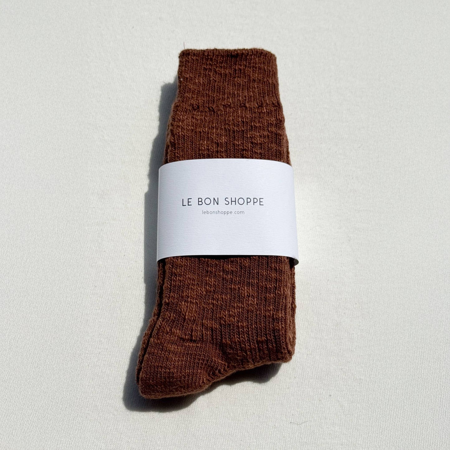 Brown sock with a white label on a light gray background