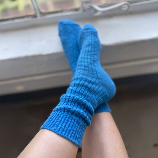 Person wearing blue socks with feet up on a windowsill against a blurred background