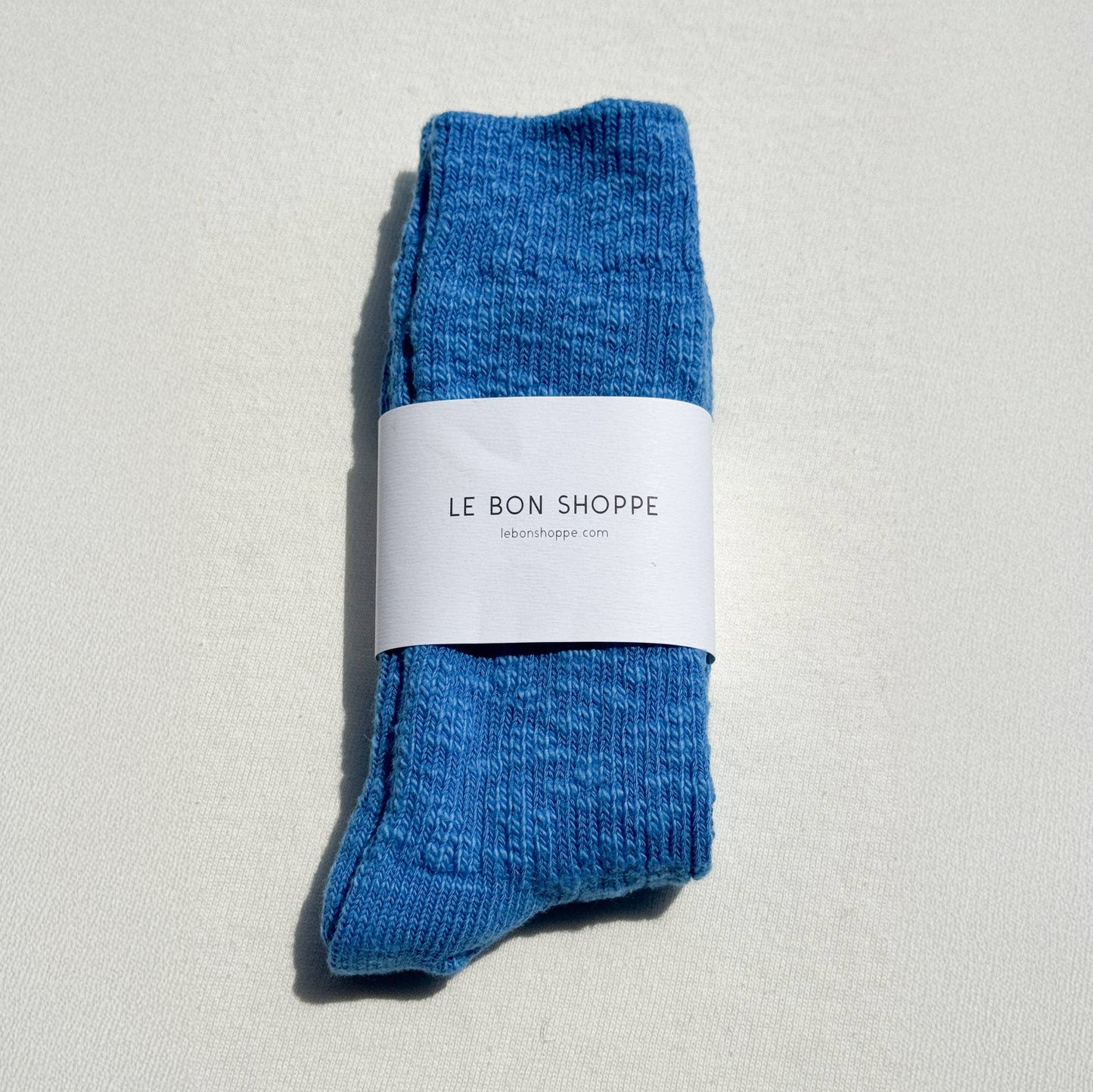 Pair of blue socks with a white label on a light gray background
