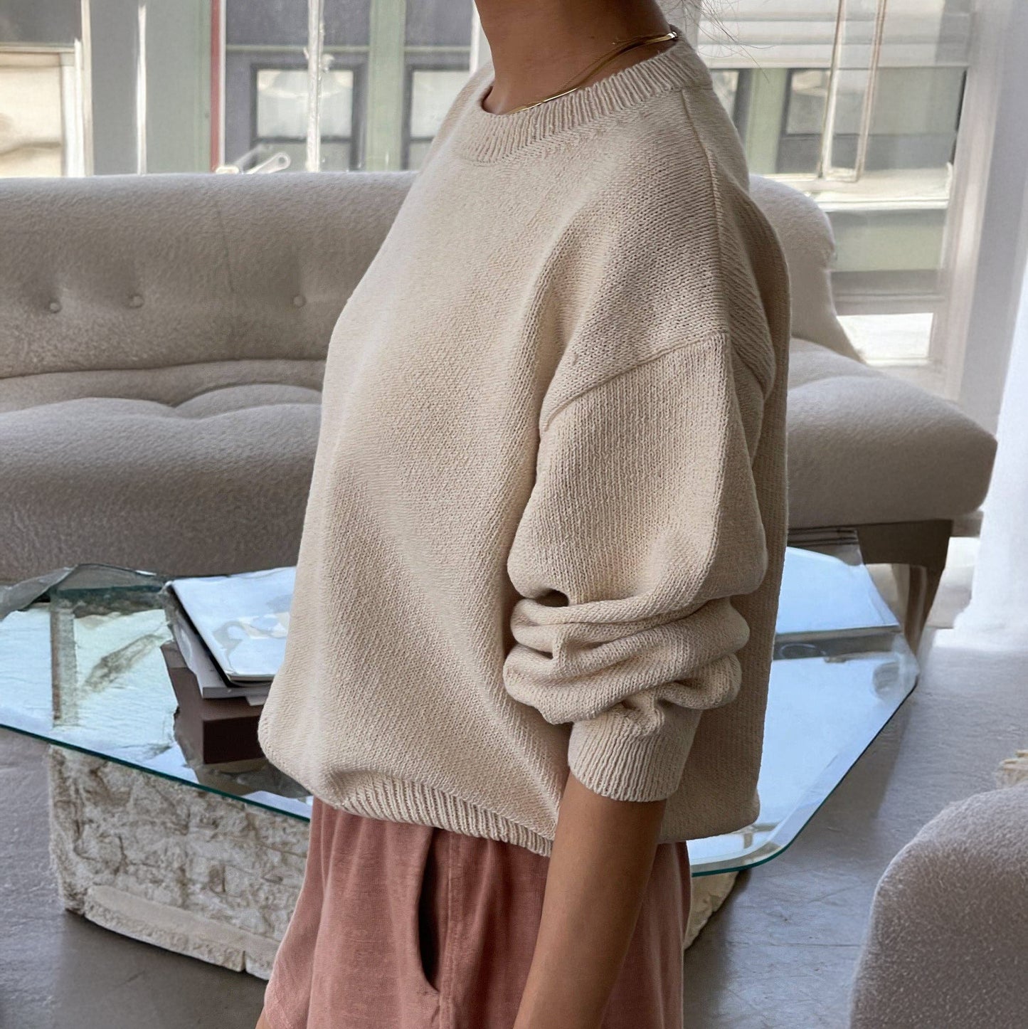 Person wearing a naturel sweater in a neutral modern living room
