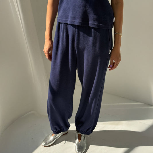 Person wearing navy blue sweatpants with a plain background