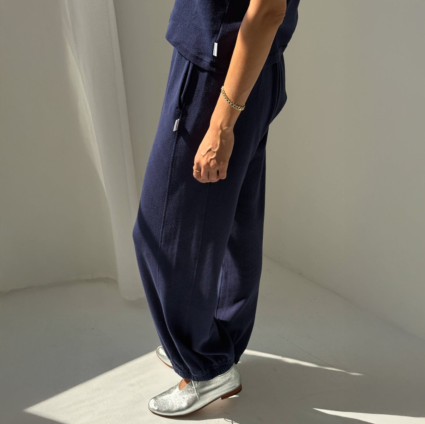 Person wearing navy blue wide-leg pants and silver shoes on a neutral background