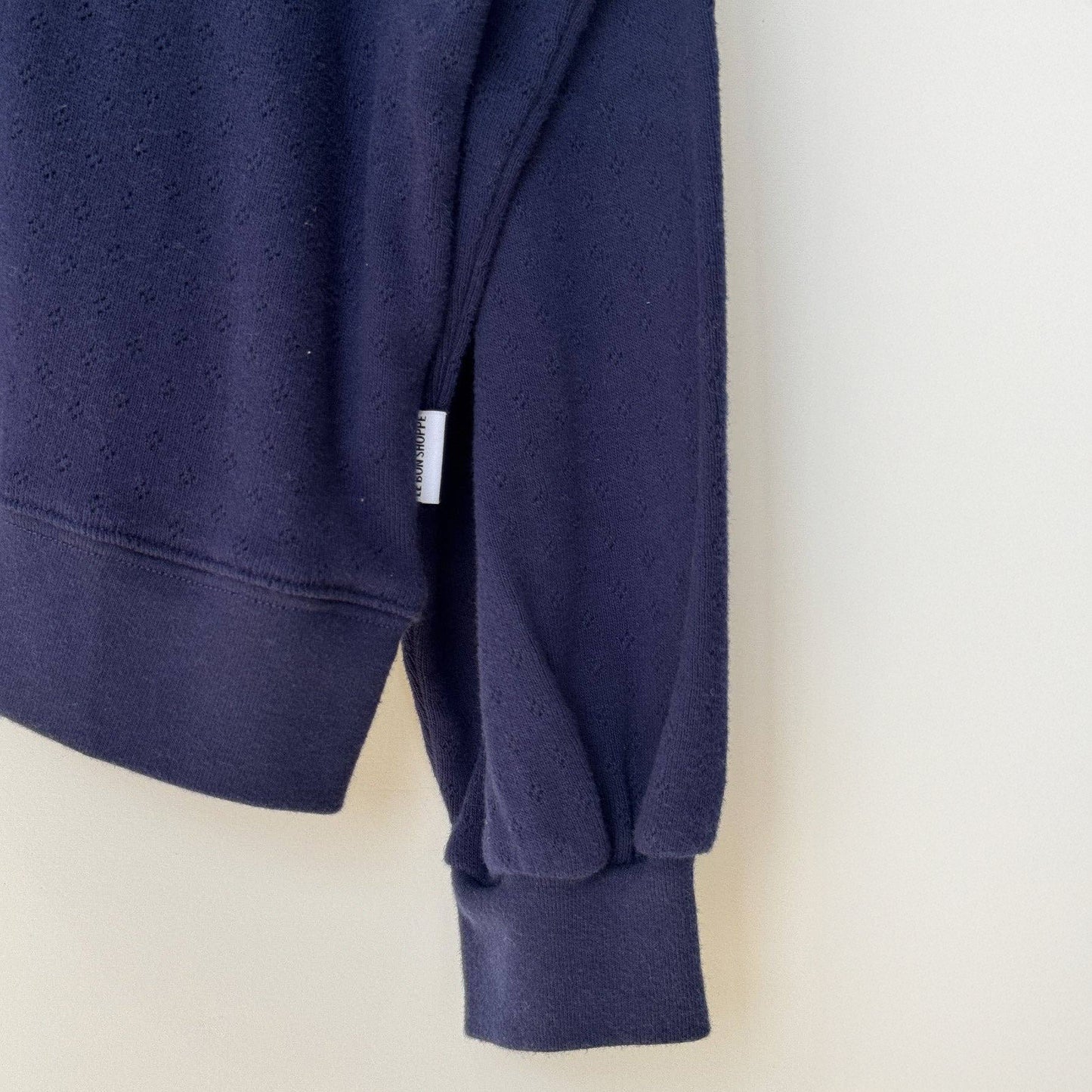 Navy blue sweatshirt with a brand logo against a light background