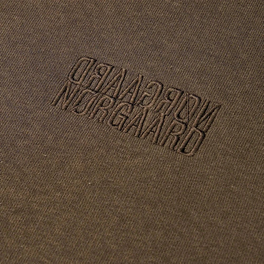 Brown fabric with embroidered text 'NORGAARD NORGAAARD' on a brown background