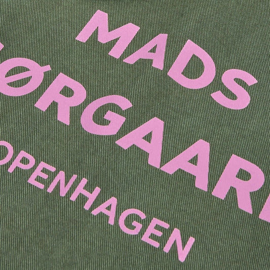 A close up of a green tote bag with pink text displaying 'MADS MØRGAARD COPENHAGEN'.