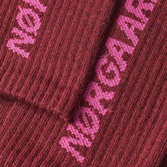 Close-up of a maroon knitted sock with pink embroidered text