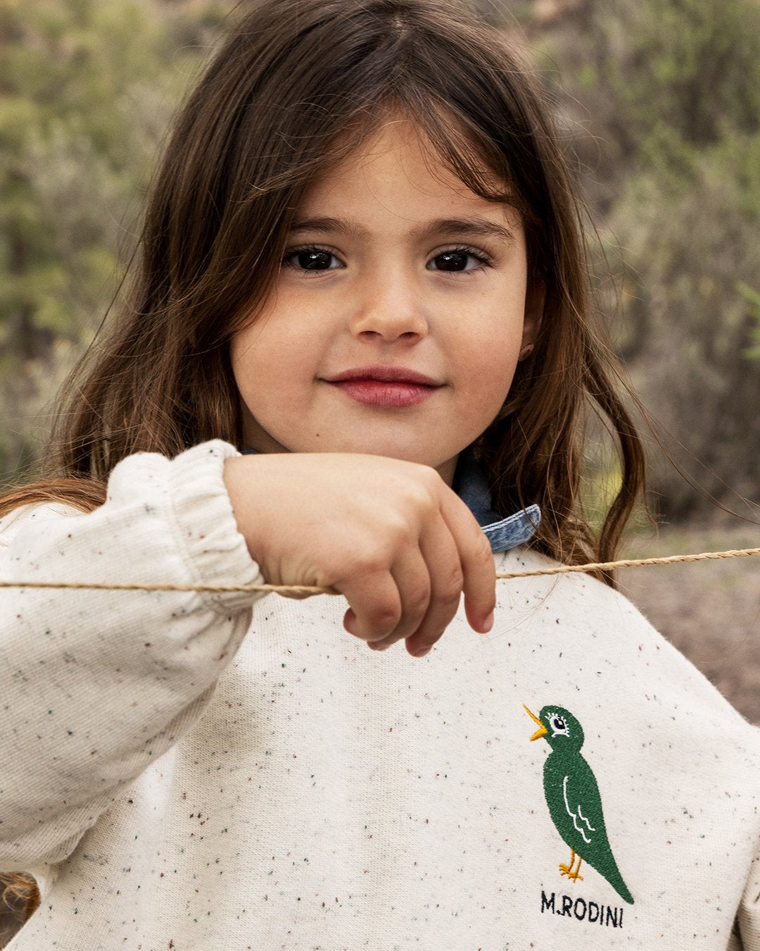 Young girl holding a stick outdoors with a blurred natural background