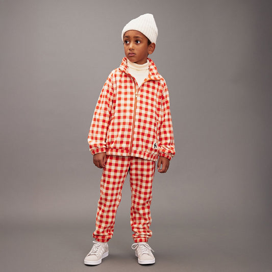 Child wearing a red and white checkered outfit with a gray background