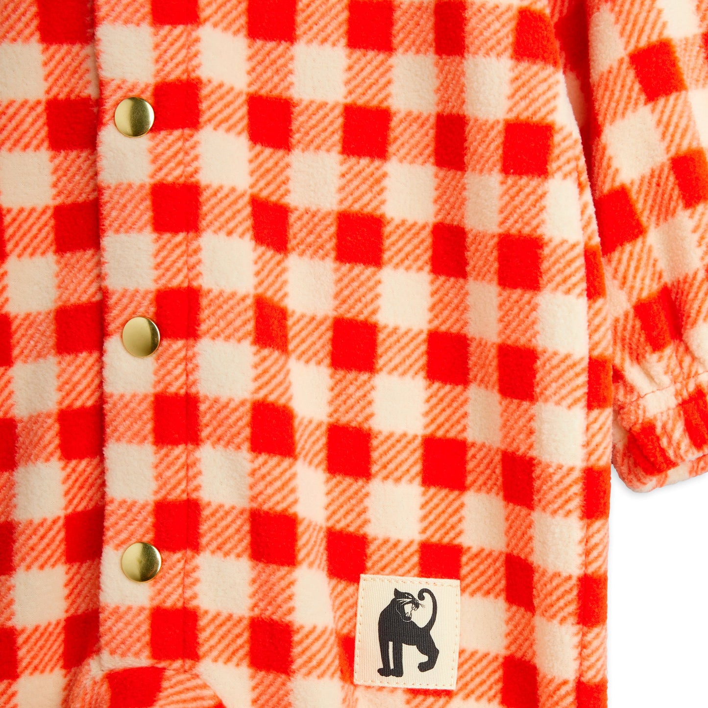 Close-up of a red and white checkered shirt with a brand label featuring a cat icon.