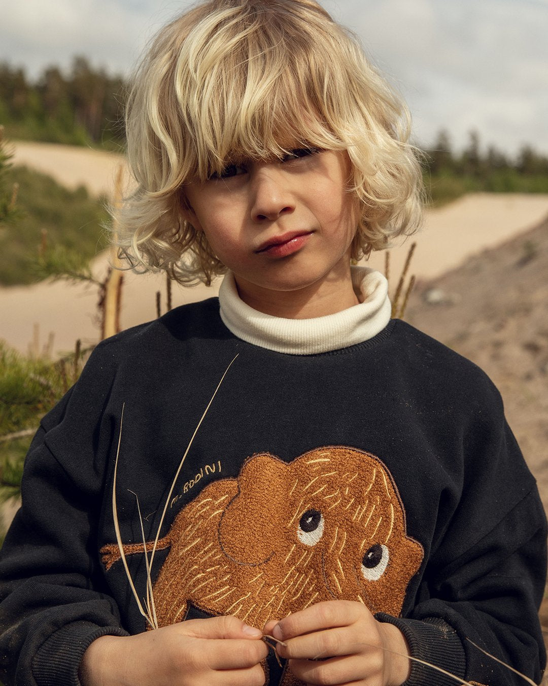 Child wearing a black sweater with a mammoth design outdoors