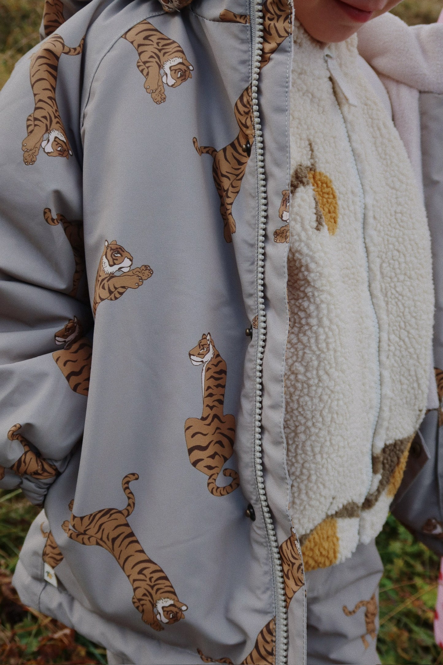 Gray jacket with tiger pattern and white scarf worn by a person outdoors.