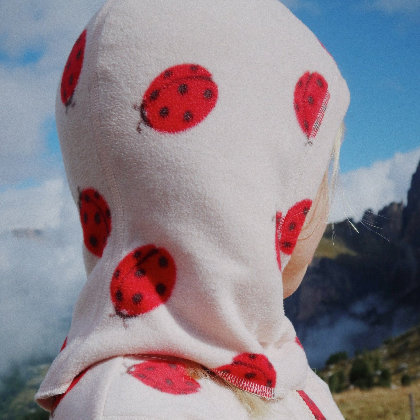 Person wearing a hoodie with ladybug pattern in an outdoor setting