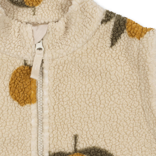 Close-up of a textured fabric with orange and leaf patterns on a beige background