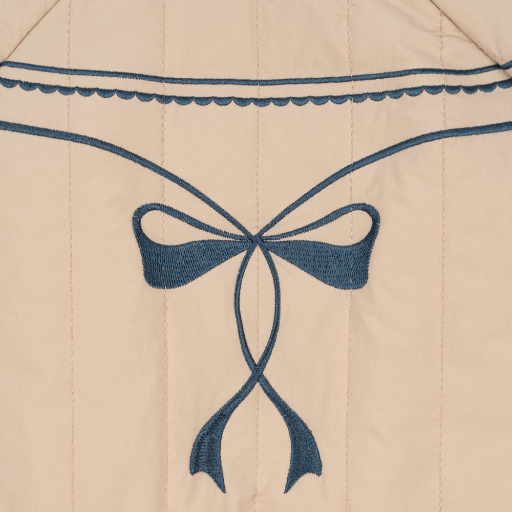 Beige fabric with a blue embroidered bow design
